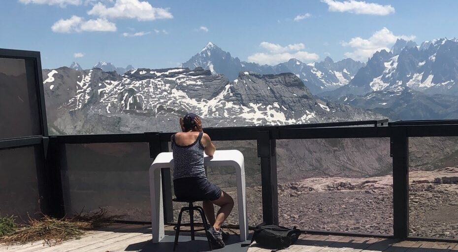 Une personnes écoute du son avec Losonnante face au paysage de la chaîne du Mont Blanc